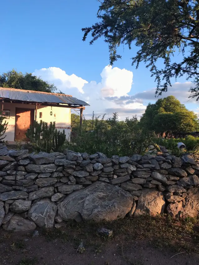 La casa de adobe, detrás de la pirca de piedra
